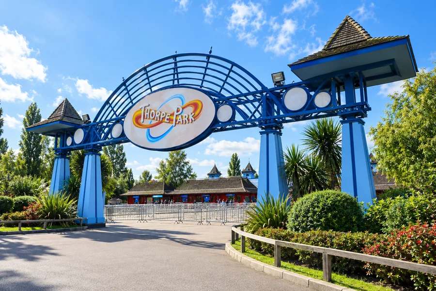 Portale d’ingresso blu e insegna di Thorpe Park in una luminosa mattina