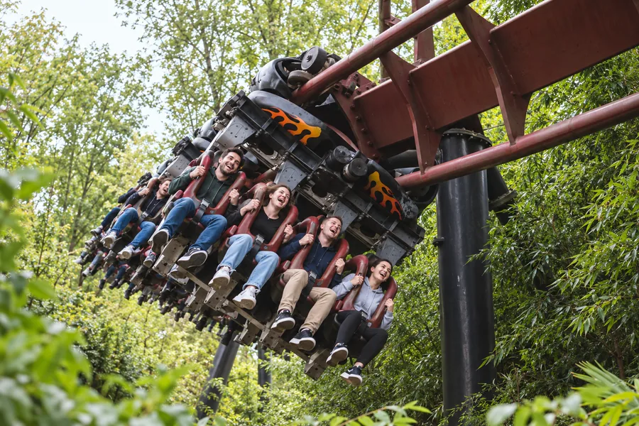 Treno sospeso sotto il binario di Nemesis Inferno sopra i vialetti immersi nel verde del parco